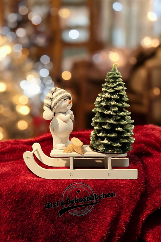 Weihnachtsdeko mit Schlitten, Schneemann, Tannebaumkerze und Holzscheiben Grün