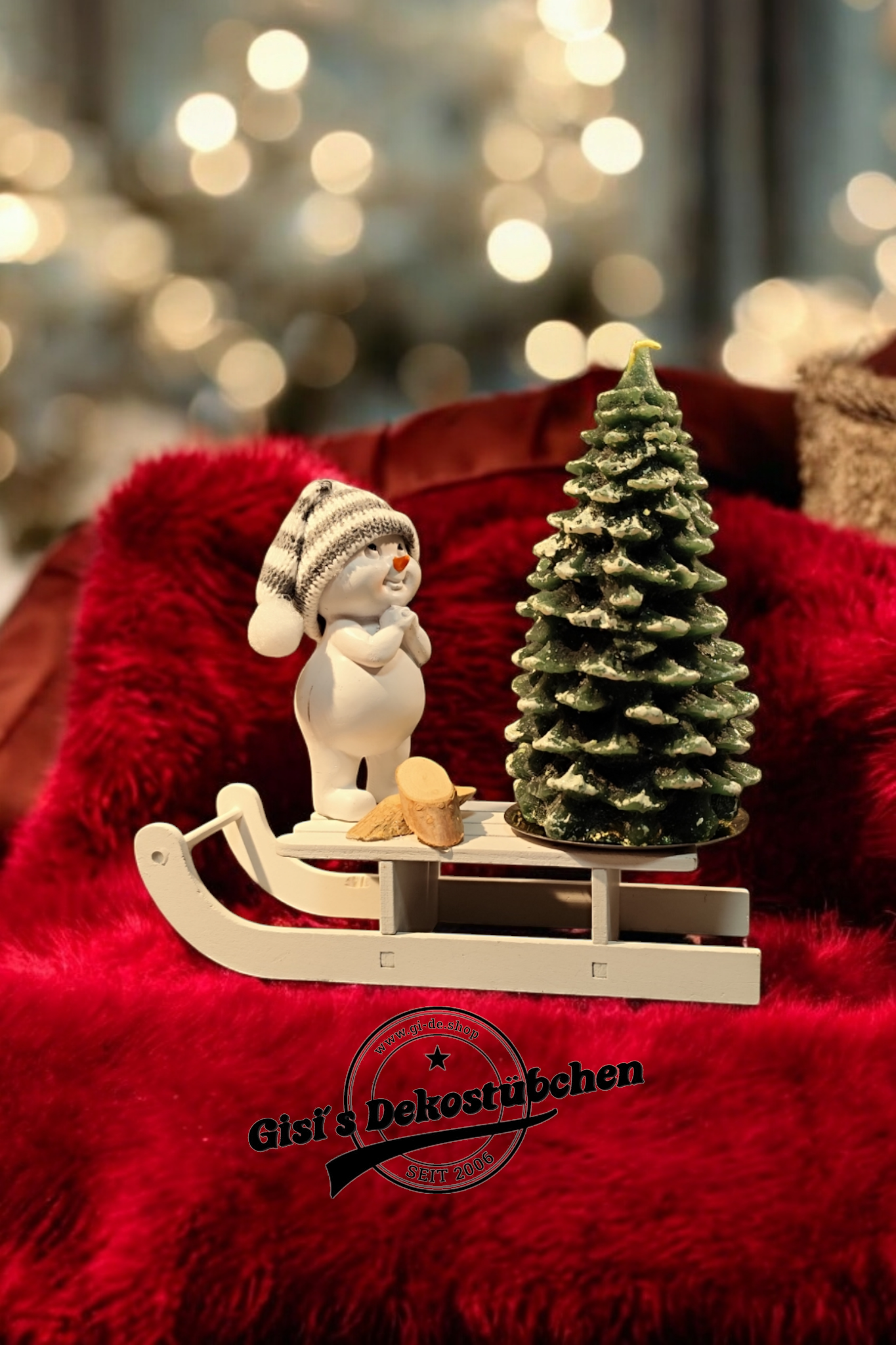 Weihnachtsdeko mit Schlitten, Schneemann, Tannebaumkerze und Holzscheiben Grün