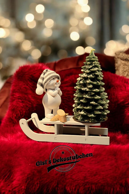 Weihnachtsdeko mit Schlitten, Schneemann, Tannebaumkerze und Holzscheiben Grün